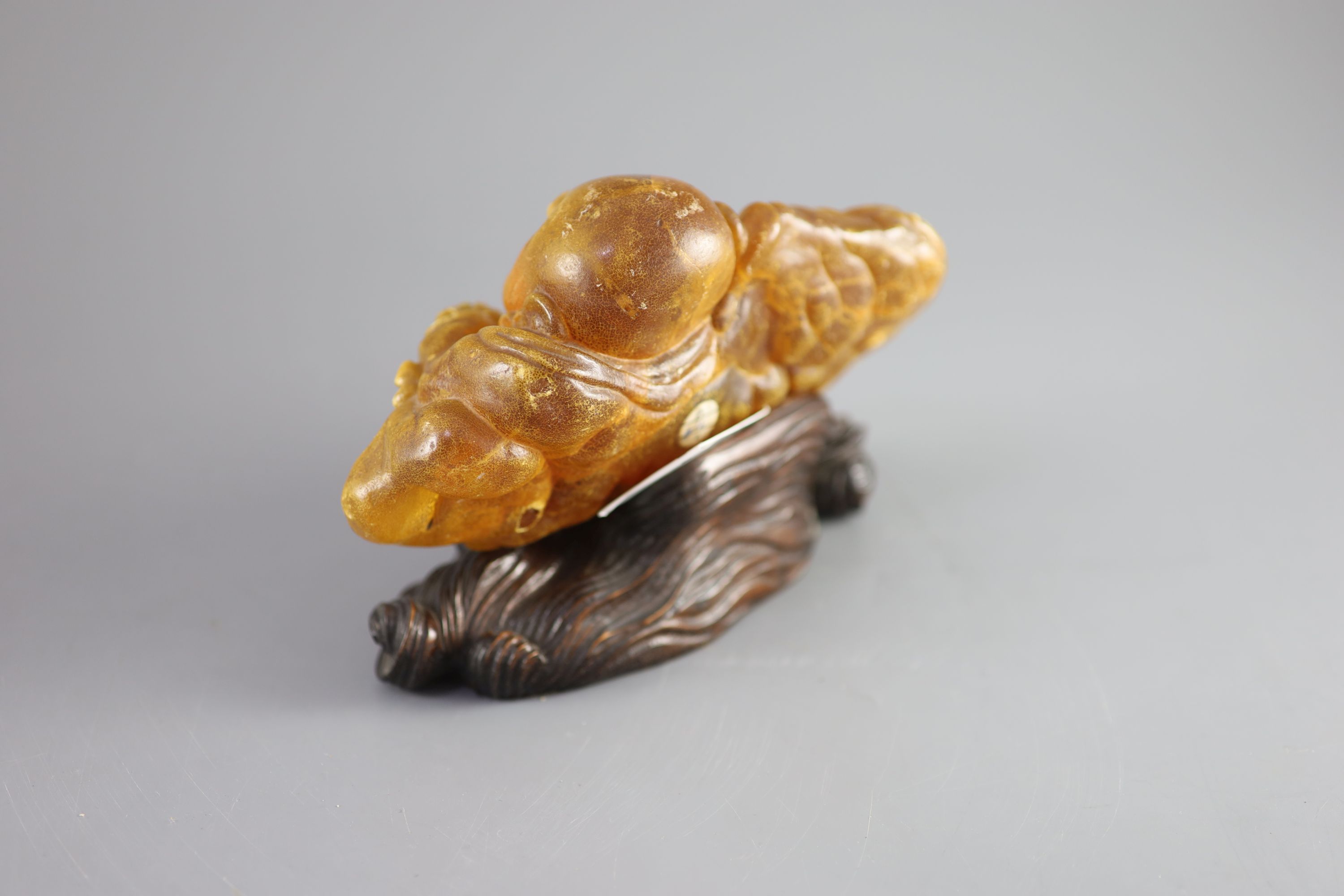 A Chinese amber figure of Buddha, 19th century, width 21.5cm